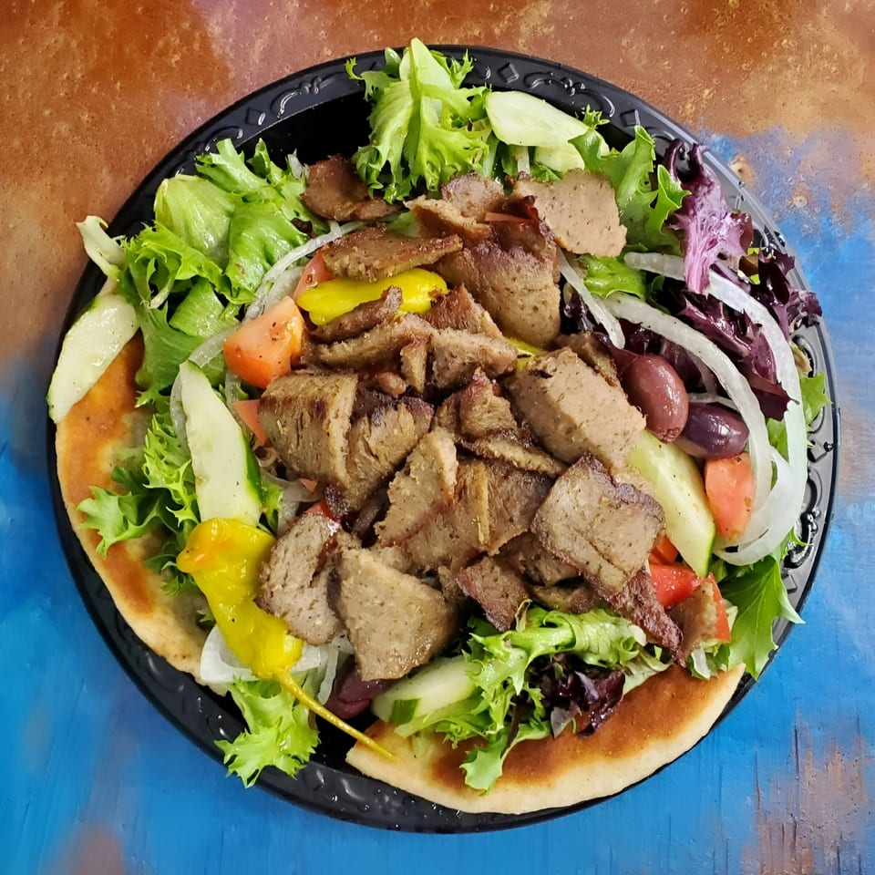 Caffé OPA's Greek gyro salad with meat, lettuce, tomatoes, cucumbers, onions, olives, and peppers.