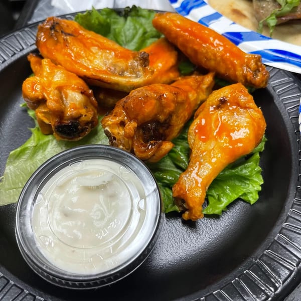 Caffé OPA's buffalo wings with ranch dressing on a bed of lettuce.