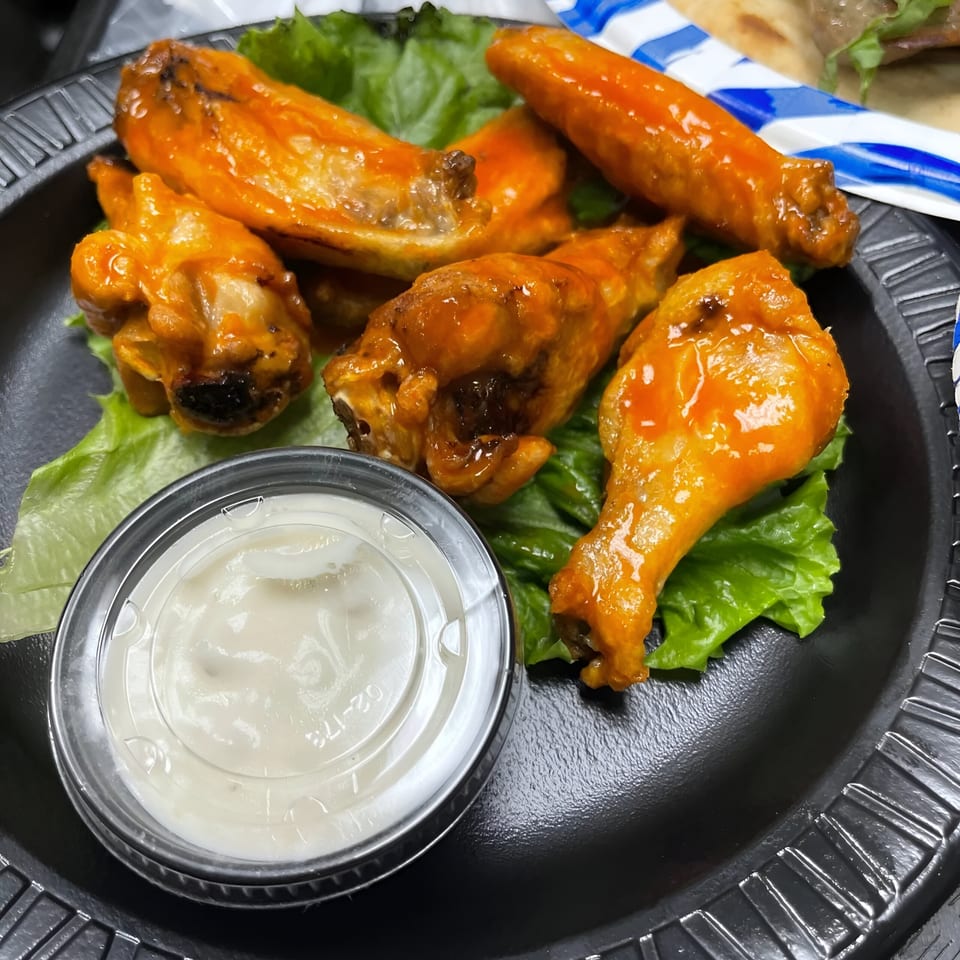 Caffé OPA's buffalo chicken wings with ranch dressing on a bed of lettuce.
